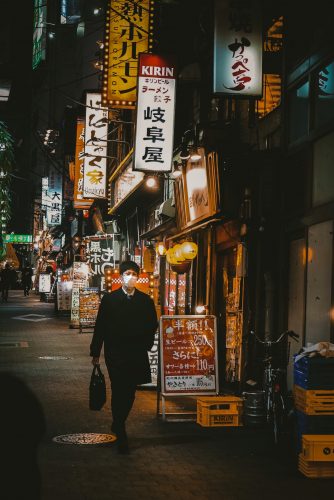 man in black jacket walking on sidewalk during nighttime