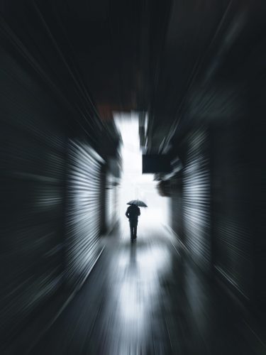 man in black jacket walking in tunnel