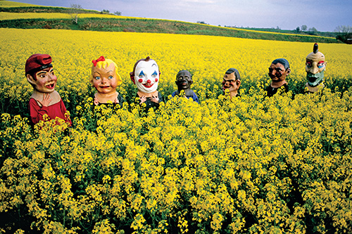 Photo by Tino Soriano | Lake Banyoles, Catalonia, Spain | 2005 | Masked people cross a mustard field on the way to a summer festival.