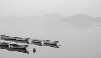 white row boats inline on body of water during foggy weather